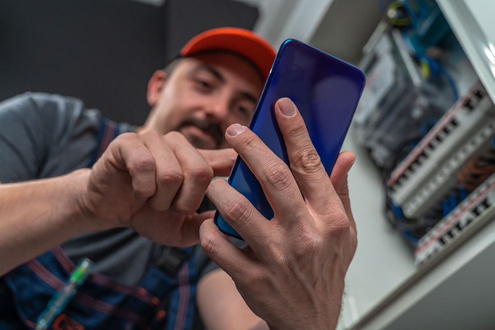 Getty Images/guirong hao Detailaufnahme eines Handwerkers, der ein Smartphone in der Hand hält, als Symbol für das Thema KI im Handwerk