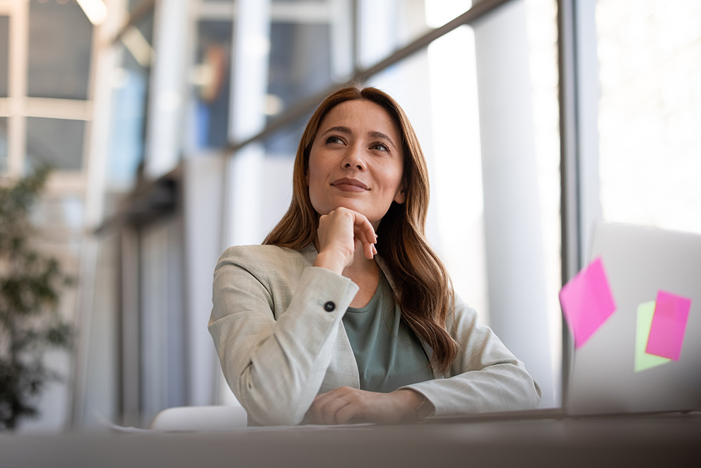Eine Frau in Businesskleidung, die am Schreibtisch sitzt, als Symbol für das Thema Produktivität steigern