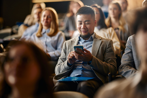 Getty Images/skynesher Mann im Publikum einer Veranstaltung blickt auf sein Smartphone – Symbolbild für Live-Untertitel auf Events