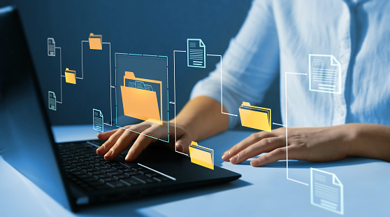 Getty Images/Galeanu Mihai Hände tippen am Laptop, umgeben von schwebenden Ordner- und Dokumentsymbolen – Symbolbild zur digitalen Personalakte
