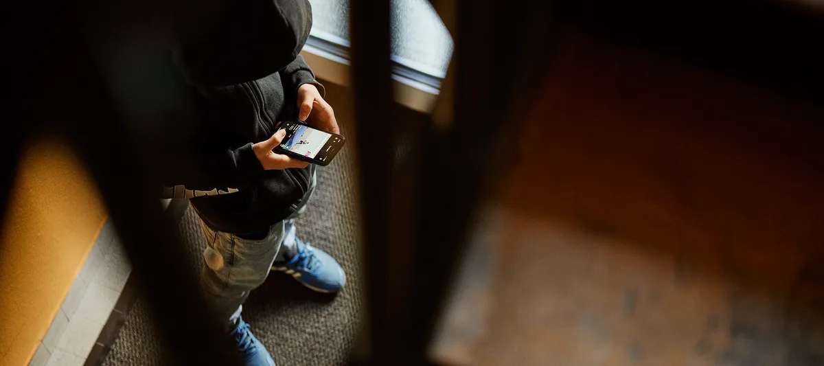 dossier-schulangst-schulfrust-schule-schweizer-elternmagazin-hg Schulfrust: Junge steht im Treppenhaus mit Handy