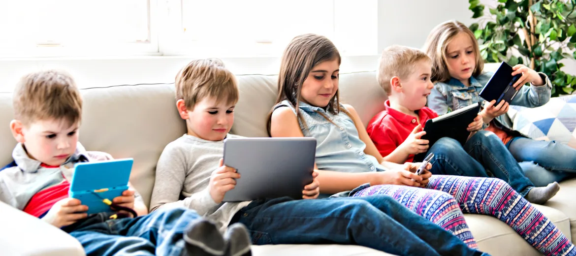 medienkonsum-kleinkinder-schaedlich-eltern-als-vorbild Ein Gruppe von Kindern auf dem Sofa starrt auf ihre Tablets.
