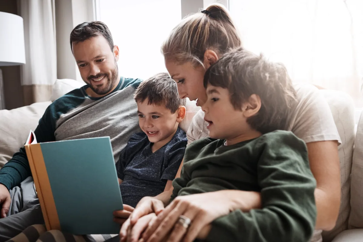 endlich-lesen-lernen-schweizer-elternmagazin-lesenlernen Lesenlernen: eine Familie schaut sich gemeinsam ein Buch an