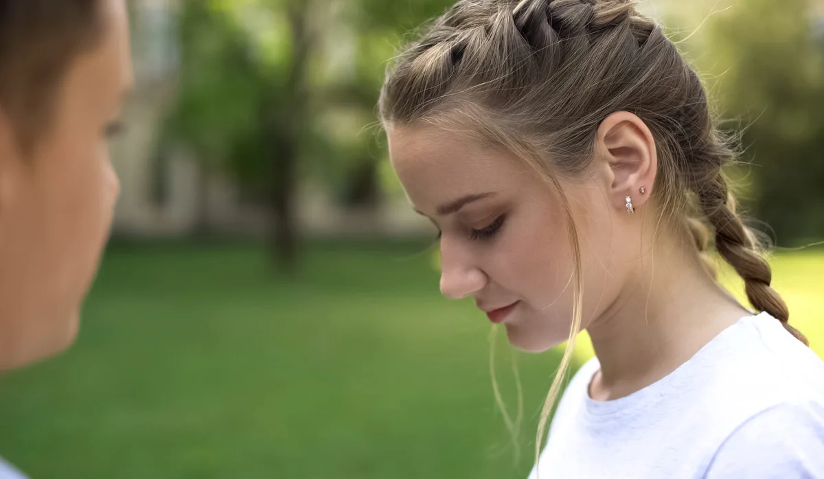 Shy teenager girl looking down, romantic date of students, awkward moment