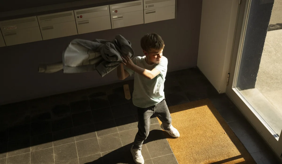 Wut: Ein Junge schmeisst seine Jacke gegen den Hauseingang