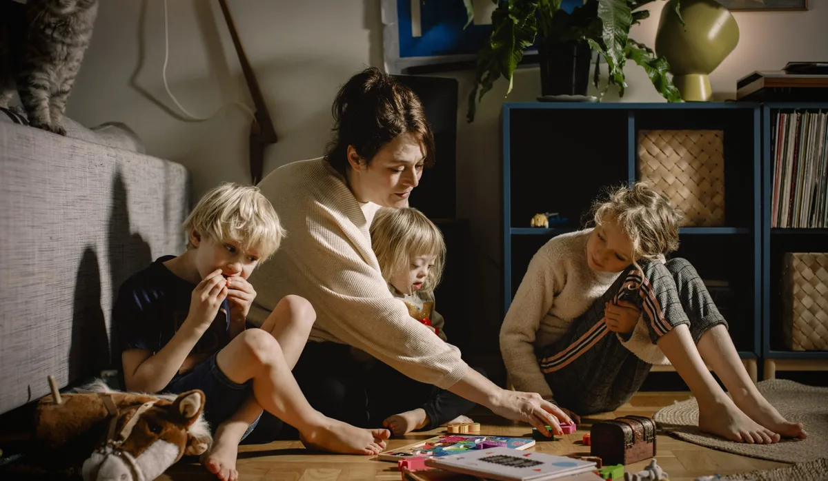 Tagesfamilien: Eine Frau beim Spielen mit drei Kindern