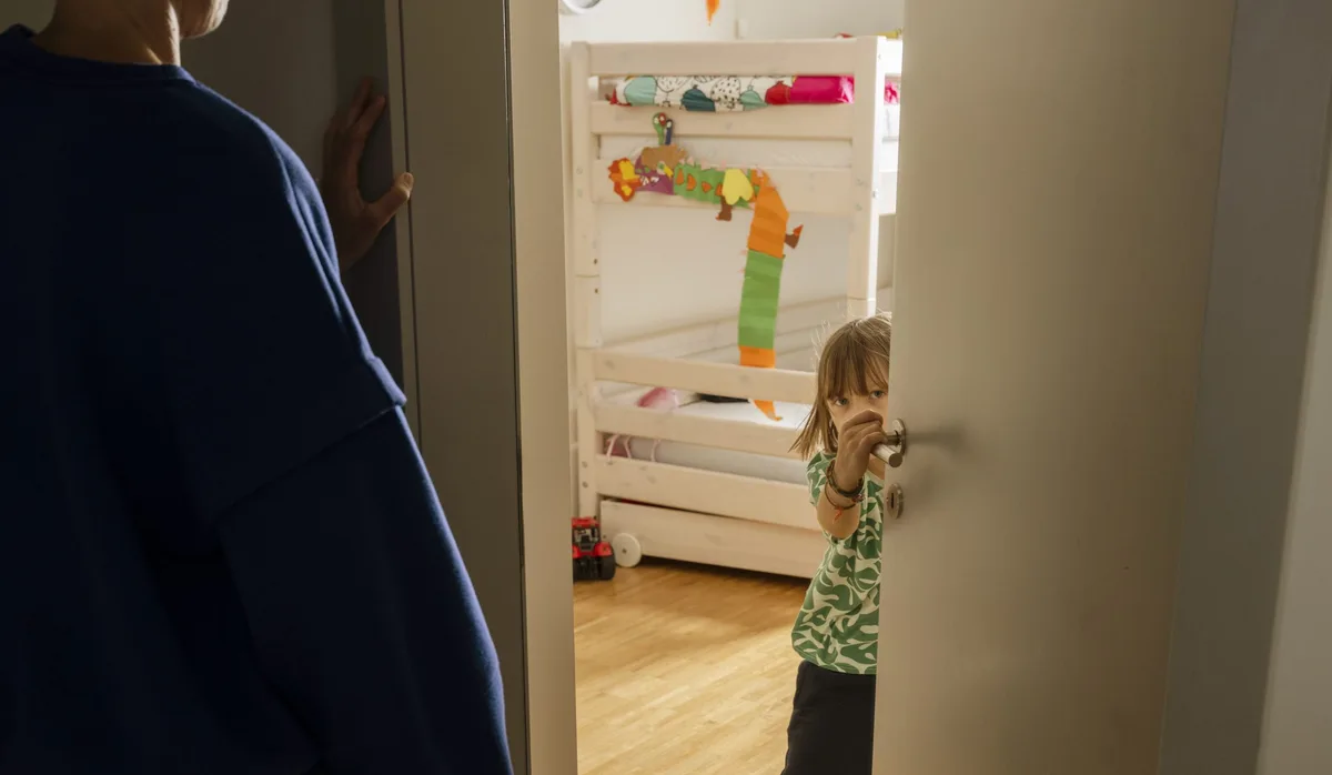 Väter und Umgang mit Wut bei Kindern: Vater steht vor Kinderzimmer; Mädchen öffnet die Tür
