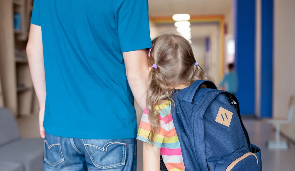 Angst, Kinderängste: Eine Primarschülerin klammert sich im Schulhaus ängstlich an ihren Vater.