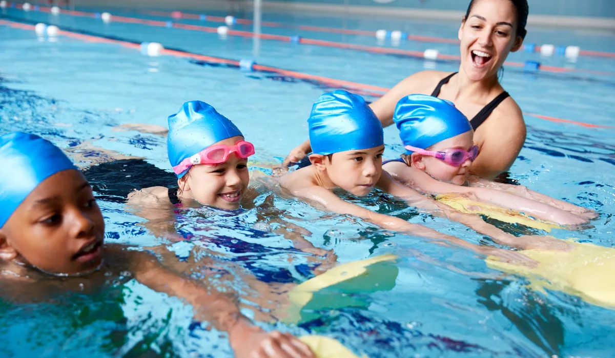 Inklusion im Schwimmunterricht: 4 Kinder und ihre Schwimmlehrerin im Schwimmunterricht