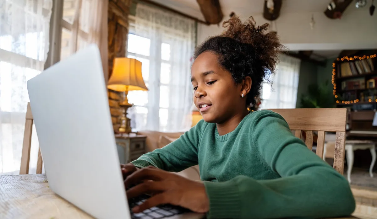 Umgang mit Künstlicher Intelligenz: ein Mädchen sitzt zu Hause vor einem Laptop