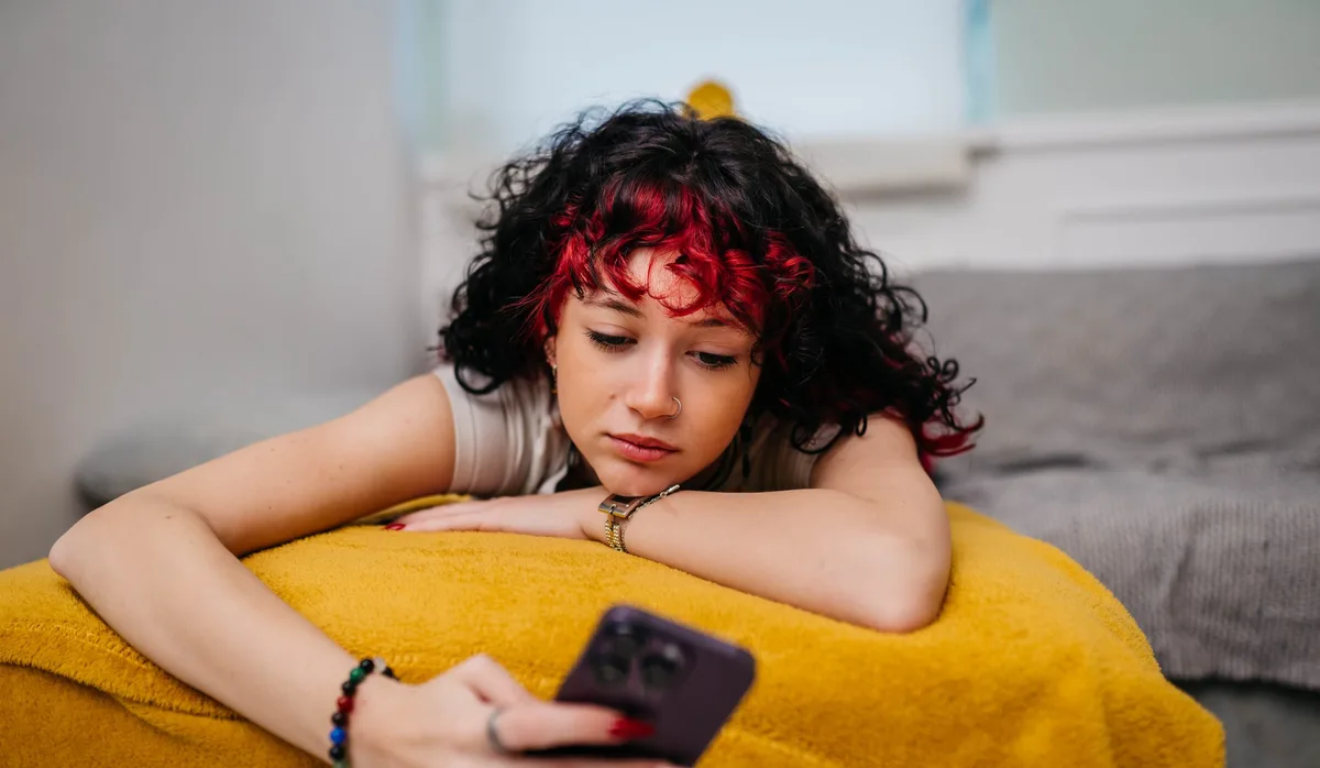 Hilfe für Jugendliche mit psychischen Problemen: Eine junge Frau blickt deprimiert auf ihr Smartphone.