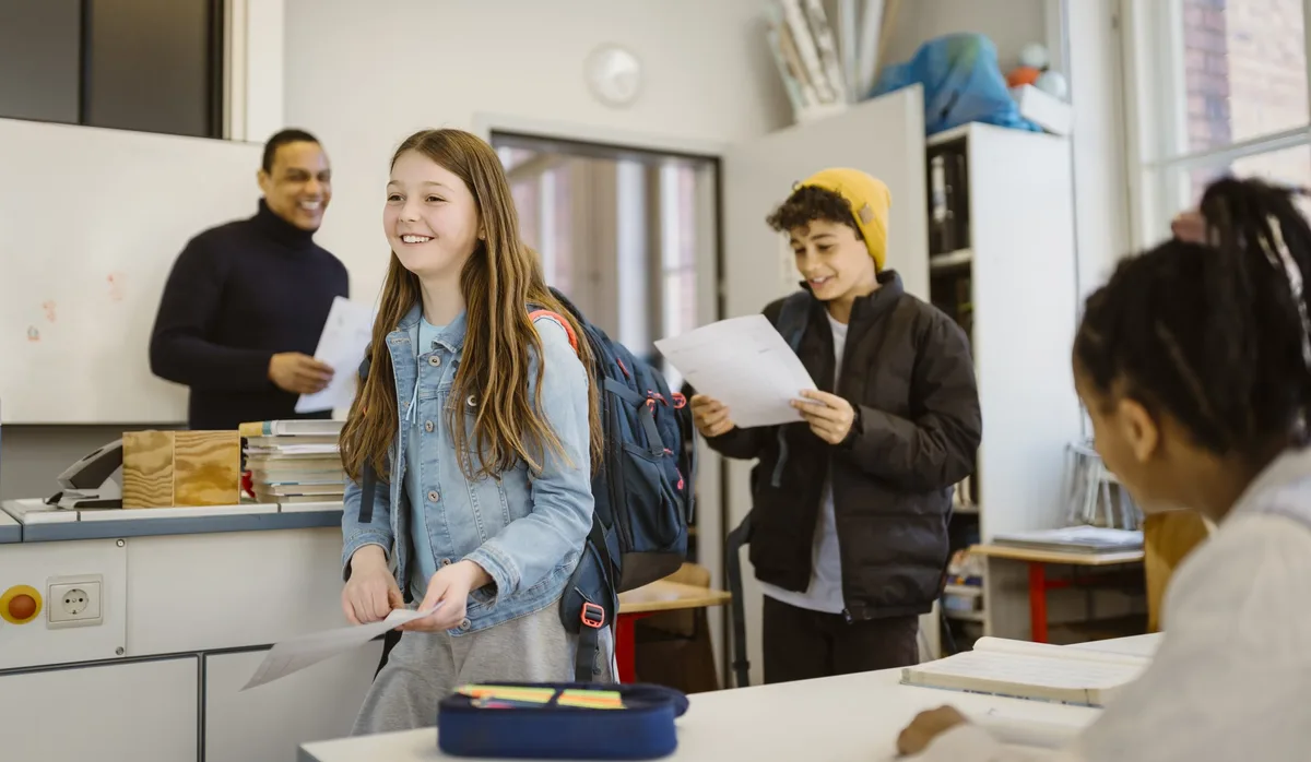 Smiling male and female students walking in classroom holding documents Schule: Jedes Kind sollte eine Chance auf Bildung bekommen