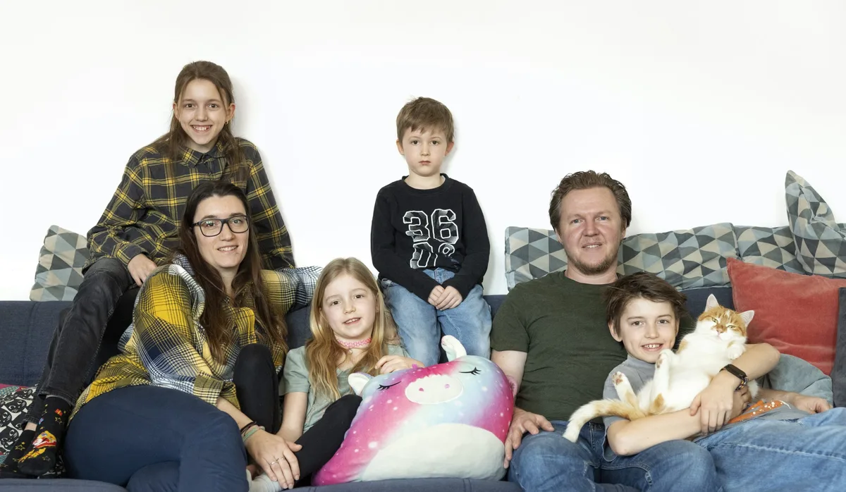 Familie mit vier Kindern und einer Katze auf dem Sofa