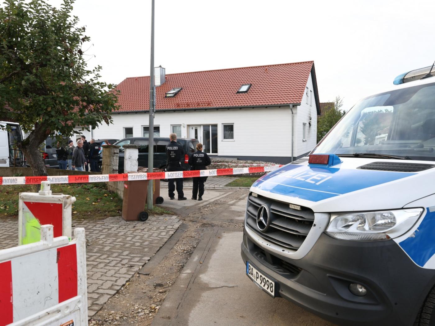 Ein Polizeifahrzeug steht an einer mit Flatterband abgesperrten Straße vor einem Tatort. Ein 60-jähriger Mann soll bei einer routinemäßigen Waffenkontrolle eine Mitarbeiterin und einen Mitarbeiter des Landratsamts Neumarkt in der Oberpfalz erschossen haben. Foto: Daniel Löb/dpa