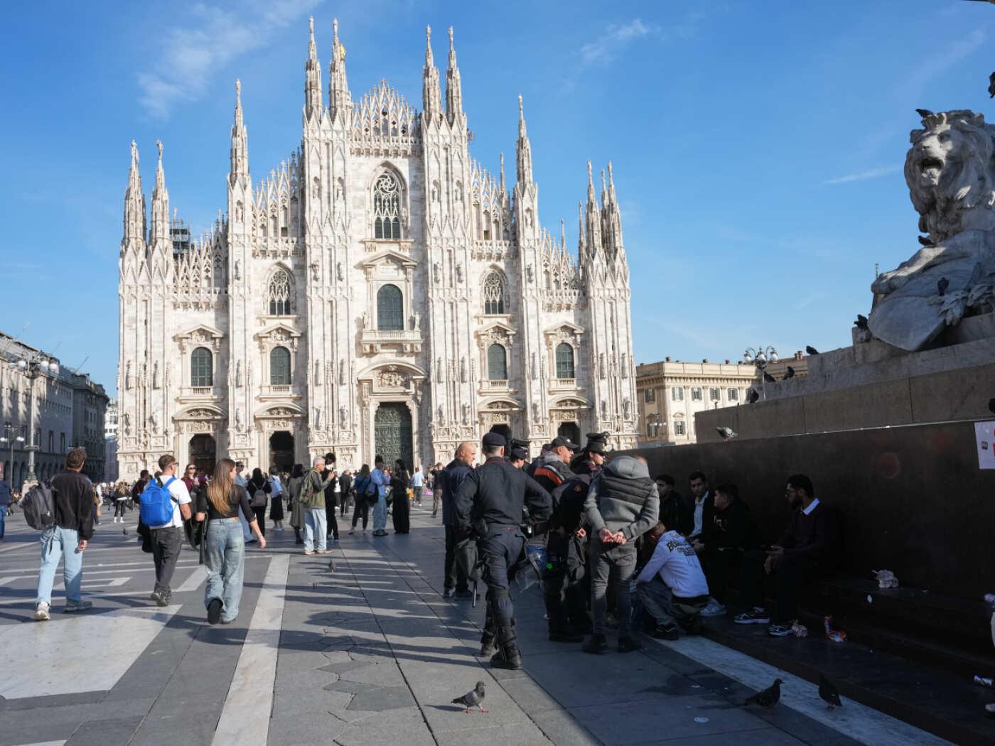 Carabinieri sprechen auf der Piazza del Duomo mit Passanten - einen Tag, nachdem Randalierer mit der Polizei zusammengestoßen waren, Geschäfte geplündert und Gebäude in Brand gesetzt hatten. Foto: Luca Bruno/AP/dpa