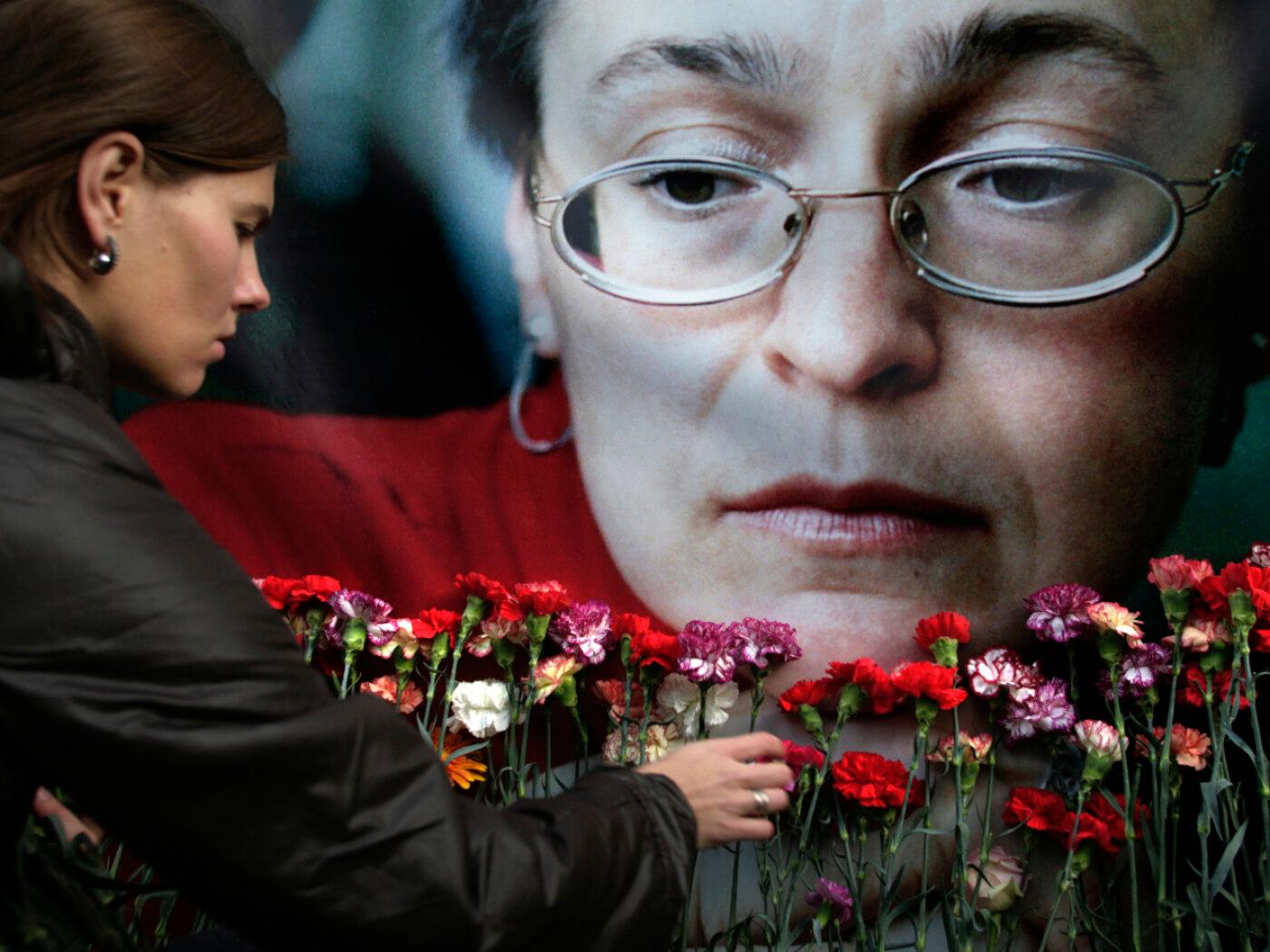 ARCHIV - Eine Frau legt Blumen vor einem Porträt der ermordeten russischen Journalistin Anna Politkowskaja nieder. Foto: Pavel Golovkin/AP/dpa