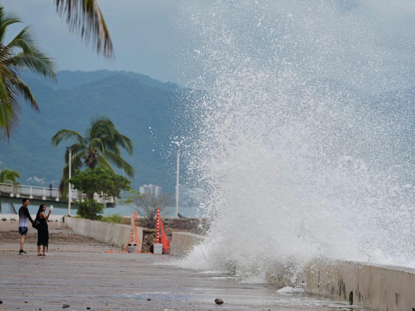 dpatopbilder - Touristen fotografieren, wie Wasser gegen die Mauer an der Küste spritzt, während sich Hurrikan «Simon» nähert. Foto: Fernando Llano/AP/dpa