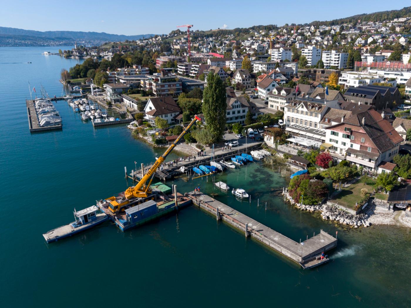 Mittels Pneukran verschieben Arbeiter eine Hafenmole in Meilen. Wegen des tiefen Wasserstands des Zürichsees lag diese auf einem Pfahlstummel auf und hätte beschädigt werden können.