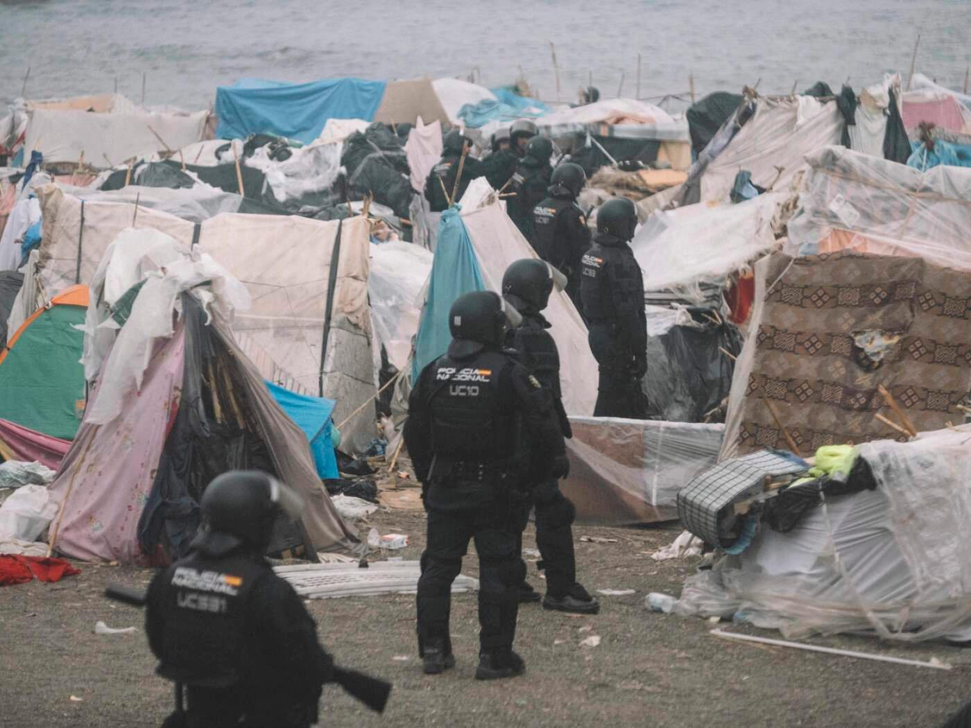 dpatopbilder - Bereitschaftspolizisten stehen während der Räumung zwischen den Unterkünften des provisorischen Migrantenlagers am Strand «El Trampolin» in Ceuta. Foto: Fabian Suspensivo/ZUMA Press Wire/dpa