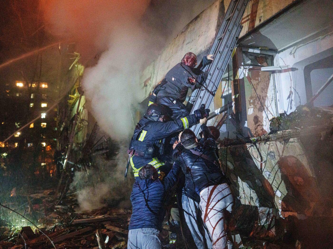 Rettungskräfte helfen einem verletzten Bewohner in Kiew über eine Leiter von seinem Balkon hinunter. Foto: Evgeniy Maloletka/AP/dpa