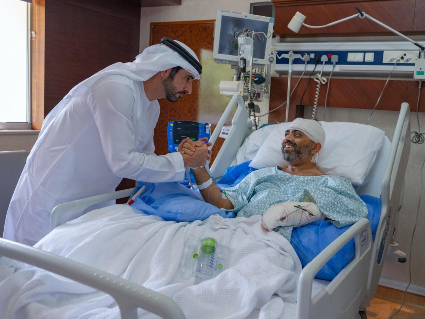 HANDOUT - Auf diesem Foto, das vom Medienbüro der Regierung von Dubai zur Verfügung gestellt wurde, besucht der Kronprinz von Dubai, Scheich Hamdan bin Mohammed bin Rashid Al Maktoum (l) den verletzten indischen Flydubai-Kapitän Smit Machchhar in einem Krankenhaus in Abu Dhabi, Vereinigte Arabische Emirate. Foto: Uncredited/Government of Dubai Media Office/AP/dpa