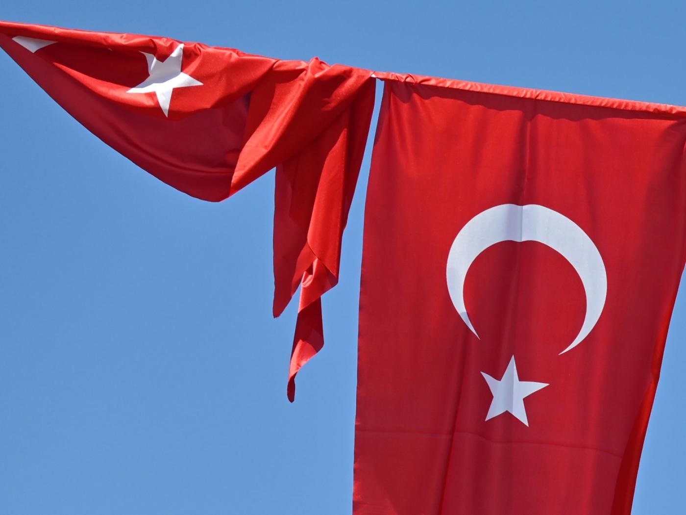 ARCHIV - Eine türkische Flagge weht vor blauem Himmel im Wind, während eine zweite Flagge aufgewickelt daneben hängt. Foto: Anna Ross/dpa/Symbolbild