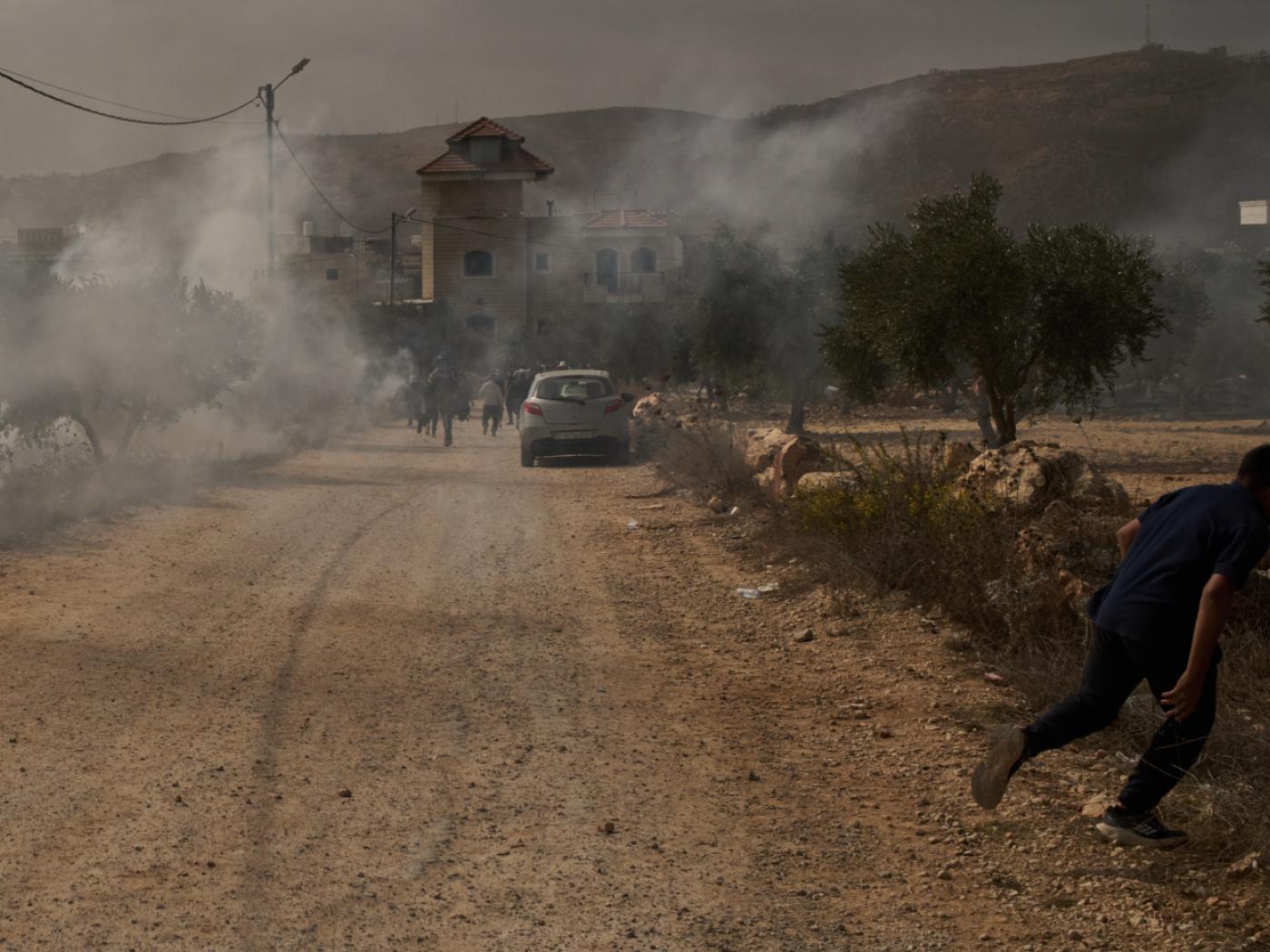 Ein palästinensischer Jugendlicher flieht vor Tränengas, das von Angehörigen der israelischen Streitkräfte nach einem Angriff von Siedlern während der Olivenernte im Dorf Abu Falah im Westjordanland abgefeuert wurde. Foto: Leo Correa/AP/dpa
