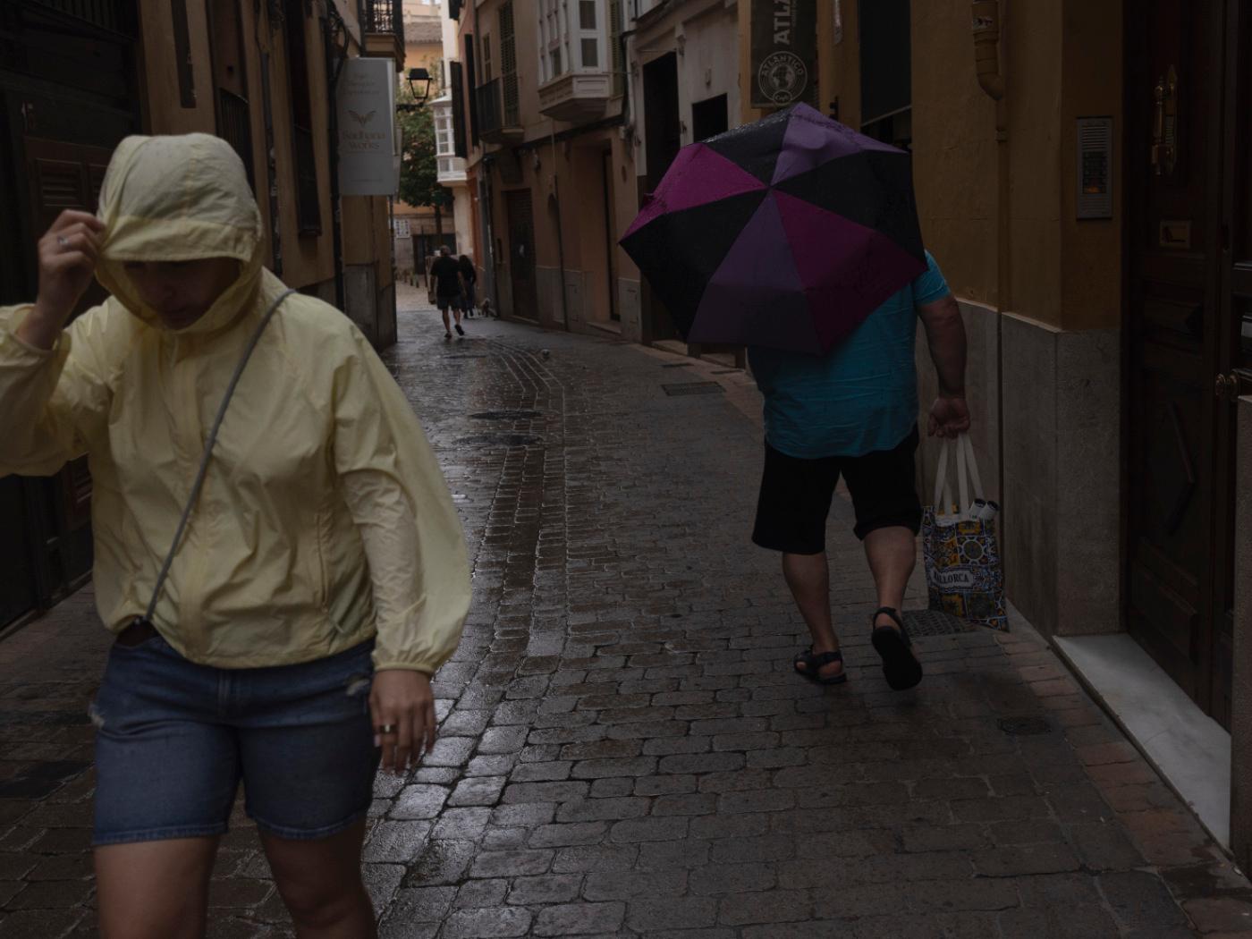 dpatopbilder - Menschen gehen im Regen durch die Innenstadt von Palma. Der Sturm "Adam" zieht gerade über die Insel hinweg, und für die Bevölkerung wurde eine rote Warnstufe ausgerufen. Foto: Clara Margais/dpa