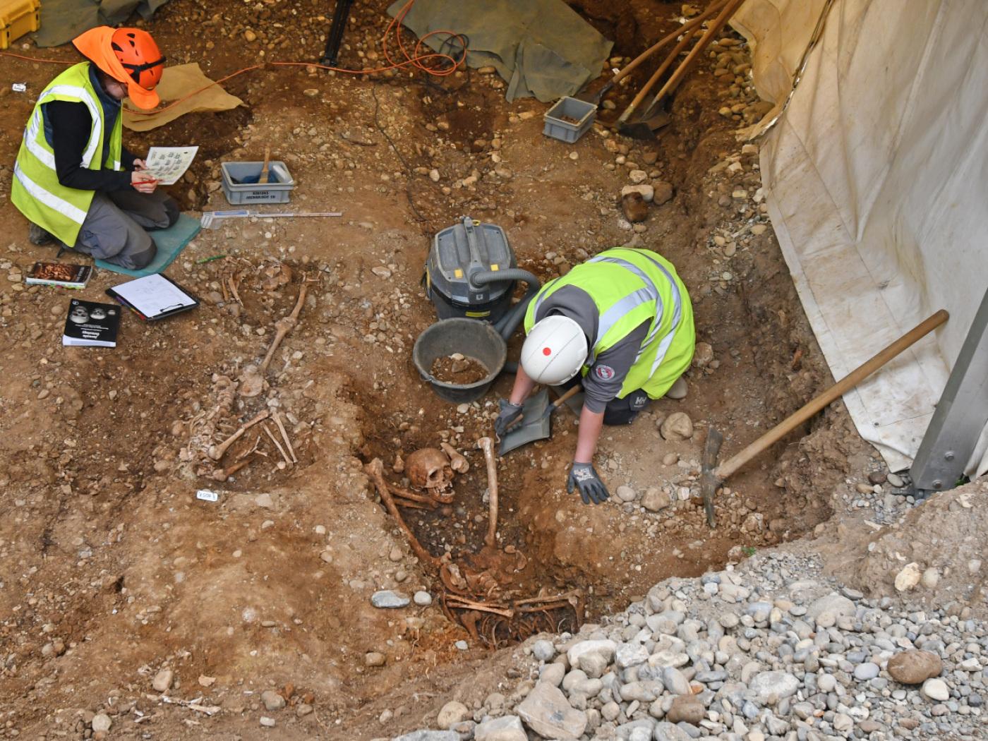 Archäologinnen haben die Skelette von zwei Personen freigelegt, deren Köpfe zwischen den Beinen liegen.