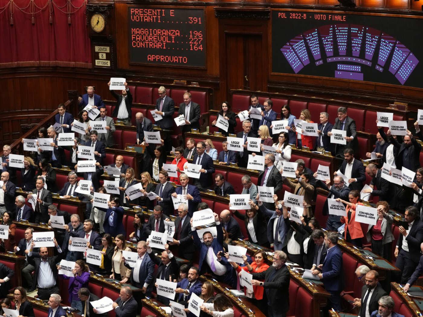 Abgeordnete protestieren, während auf einer Anzeigetafel die Ergebnisse der Schlussabstimmung über den Gesetzentwurf zum Wahlrecht in der Abgeordnetenkammer in Rom angezeigt werden. Foto: Andrew Medichini/AP/dpa