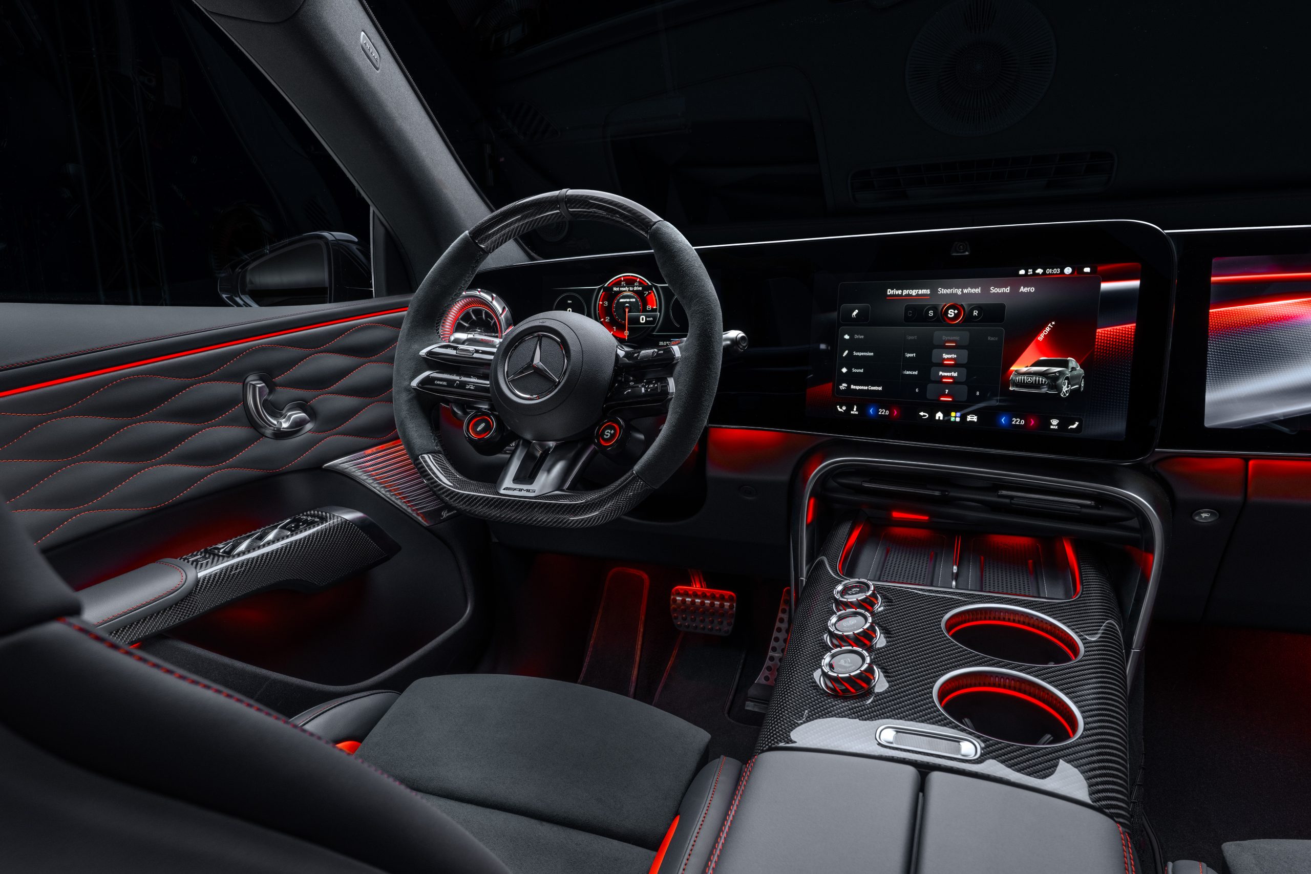 Cockpit des Mercedes-AMG GT SUV mit Sportlenkrad, breitem digitalen Display, Carbon-Elementen und roter Ambientebeleuchtung.