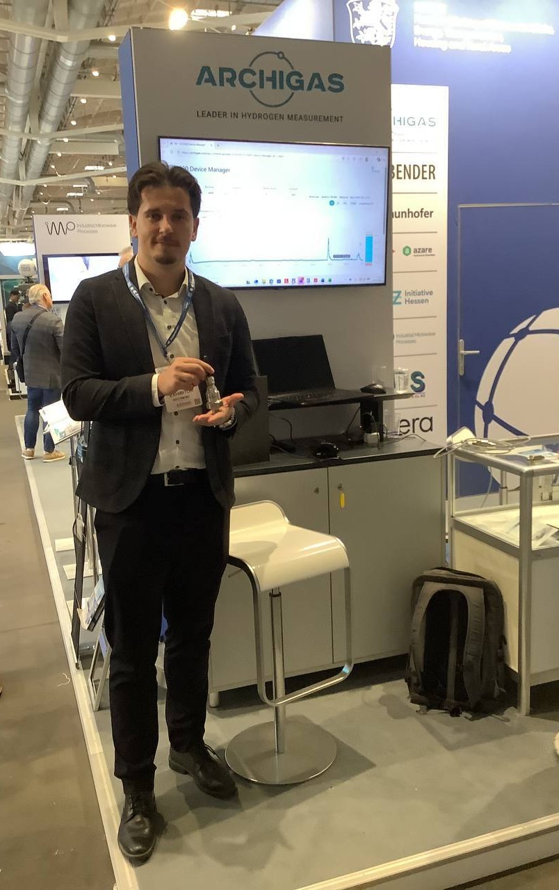 Elmedin Saliu von Archigas steht am Messestand in Hamburg und hält einen kleinen metallischen Gassensor in der Hand